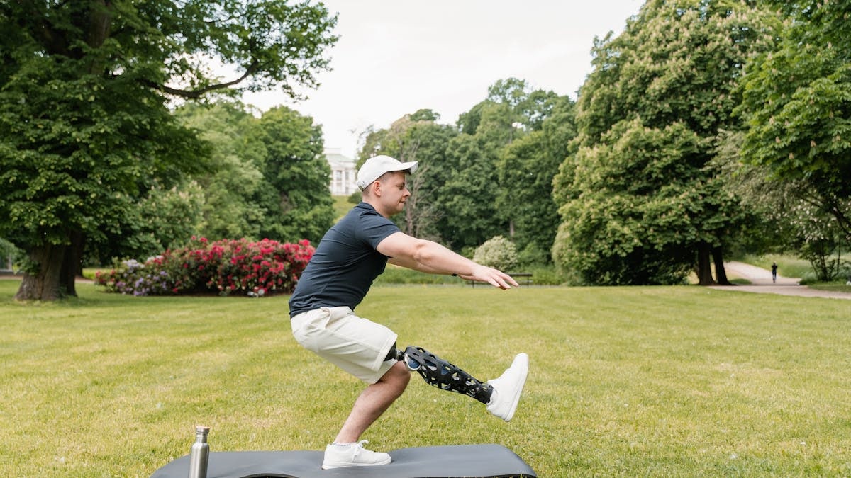 Amputee man with prosthetic leg doing yoga in a serene park. Focus on balance and strength.